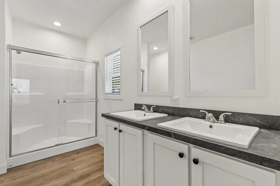 Primary bathroom with dual vanity and a glass shower