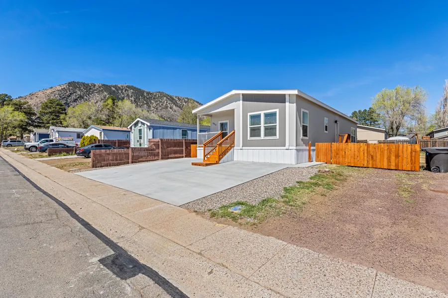 Front of the double-wide home at 5010 E Dean Ave with a wide concrete driveway and cedar fence