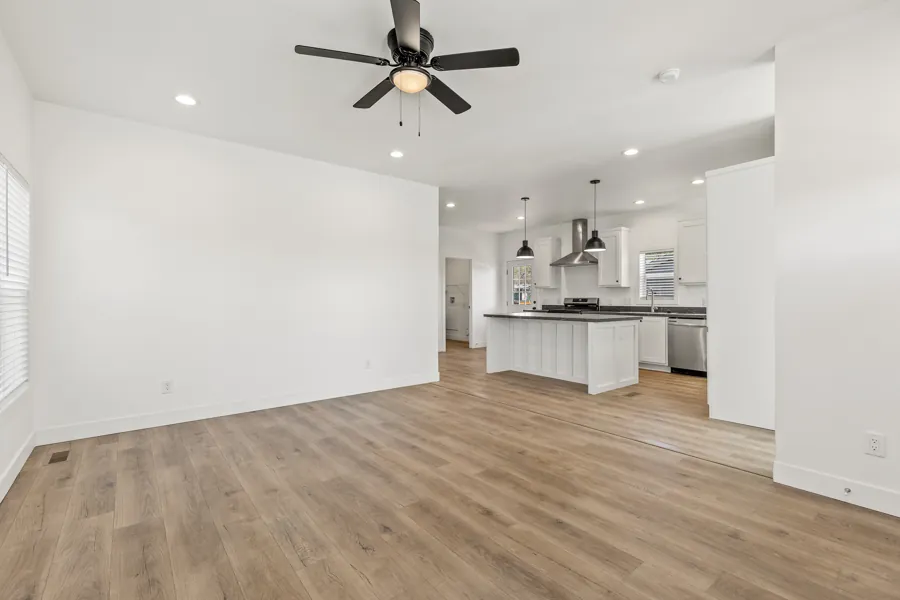 Open living room with a ceiling fan, looking toward the kitchen